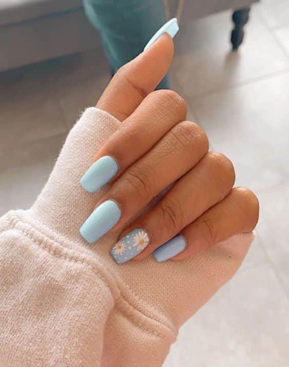 Imagem de unhas com esmalte azul claro e desenho de flor, representando a escolha de esmaltes para mulheres 60+.