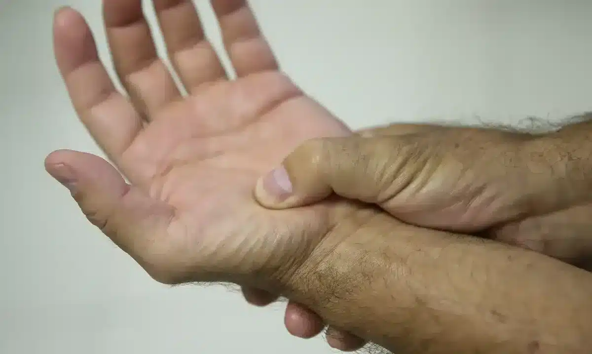 Pessoa sentindo dor no punho ao pressionar a base da palma da mão.