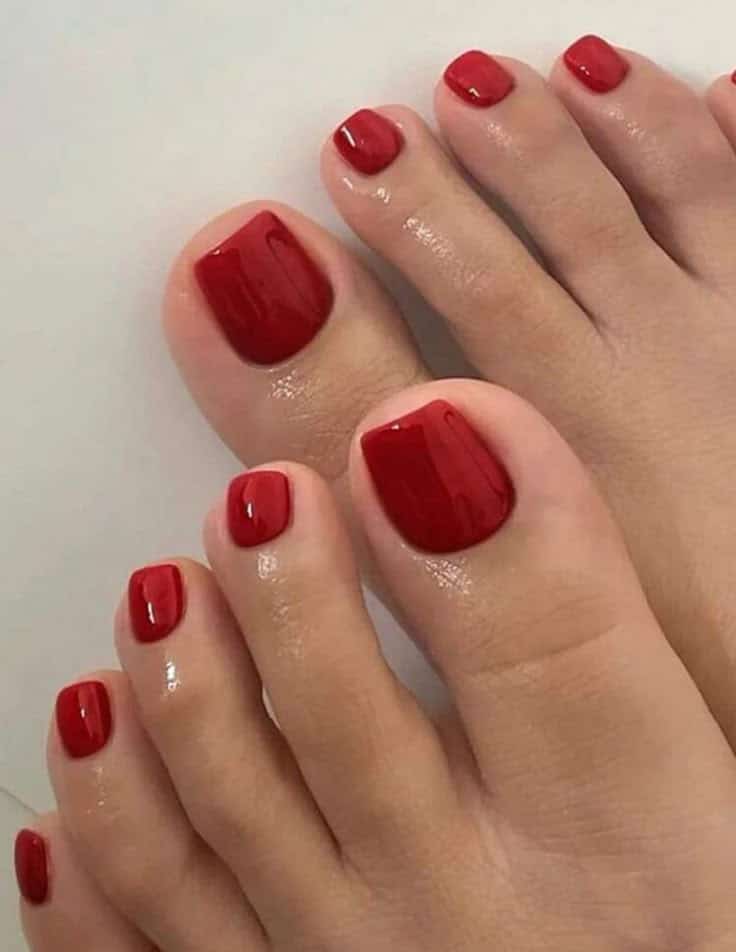 Unhas dos pés pintadas com esmalte vermelho vibrante, estilo elegante