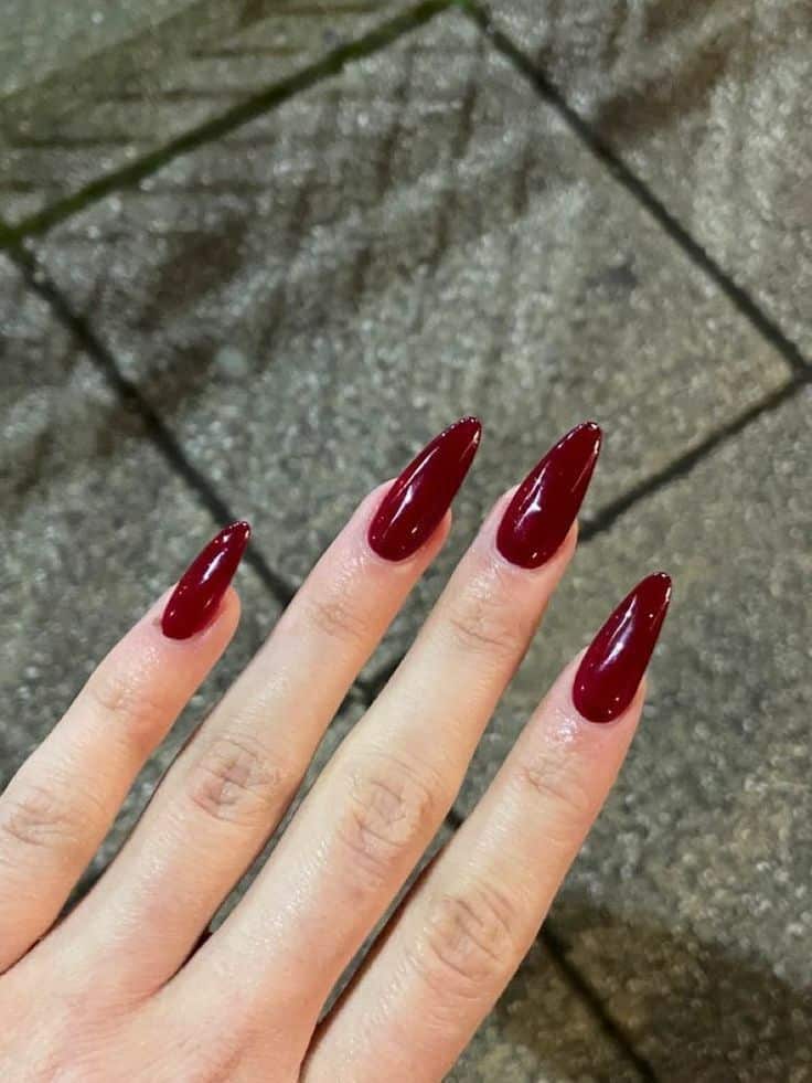 Unhas vermelhas no formato stiletto com esmalte brilhante