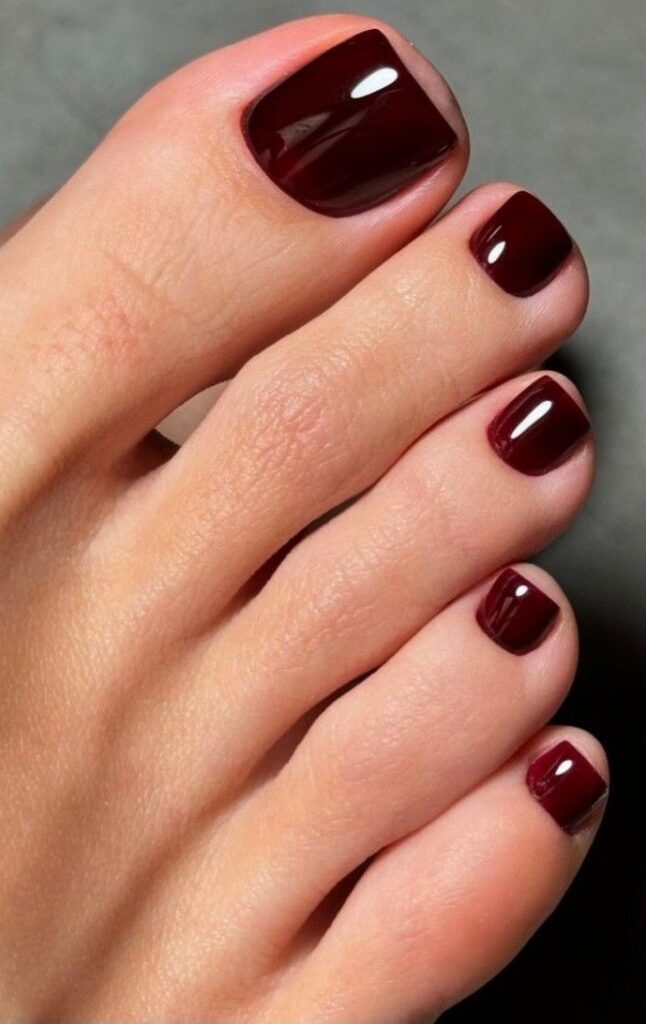 Unhas dos pés esmaltadas em tom vinho intenso, tendência do inverno
