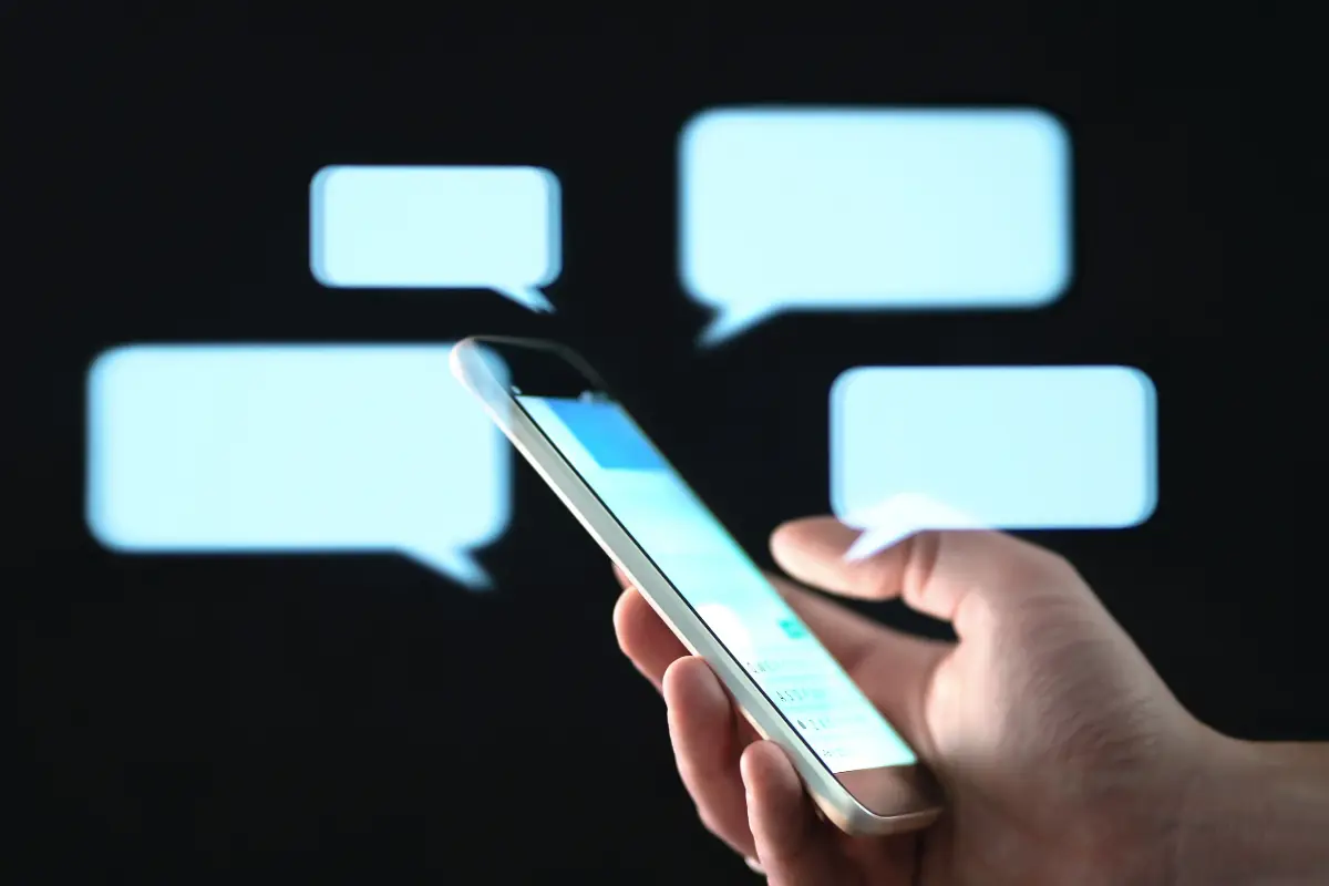 Pessoa segurando celular enquanto envia mensagem de texto carinhosa à noite.