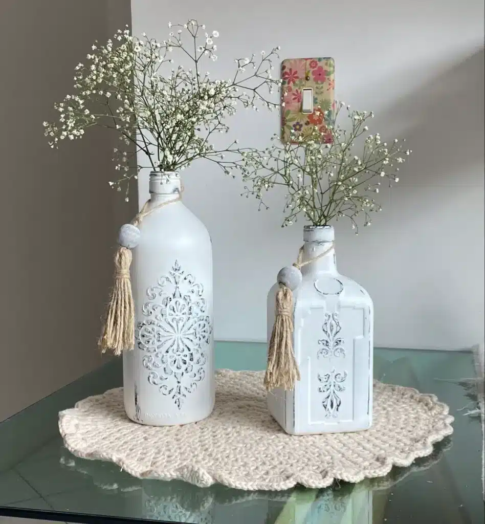 Vasos decorativos boho chic feitos de garrafas de vidro com barbante natural e detalhes em macramê simples, com flores pequenas.