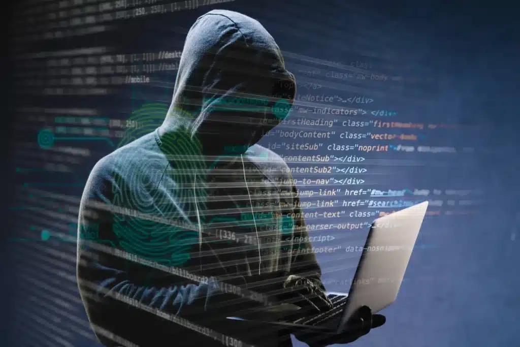 Imagem de um hacker usando um laptop com código de programação ao fundo, representando cuidados com golpes online.