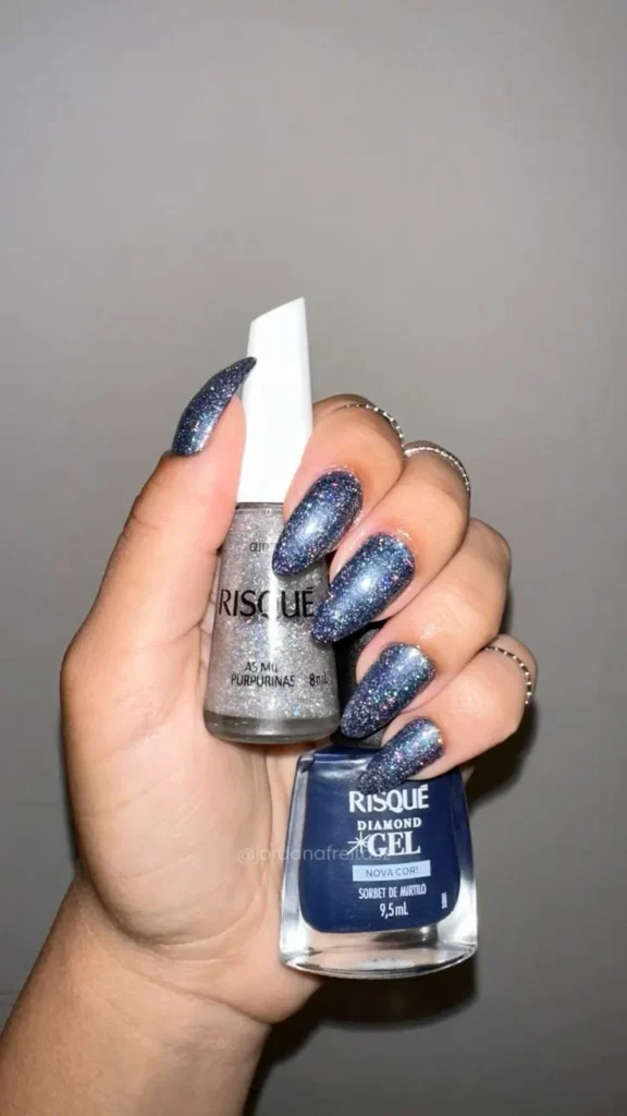 Unhas em azul escuro com glitter prateado, criando um visual festivo e brilhante.
