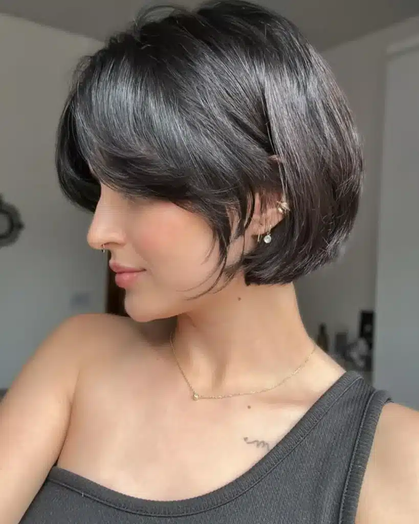 Corte bob curto com franja lateral em cabelo fino e escuro.