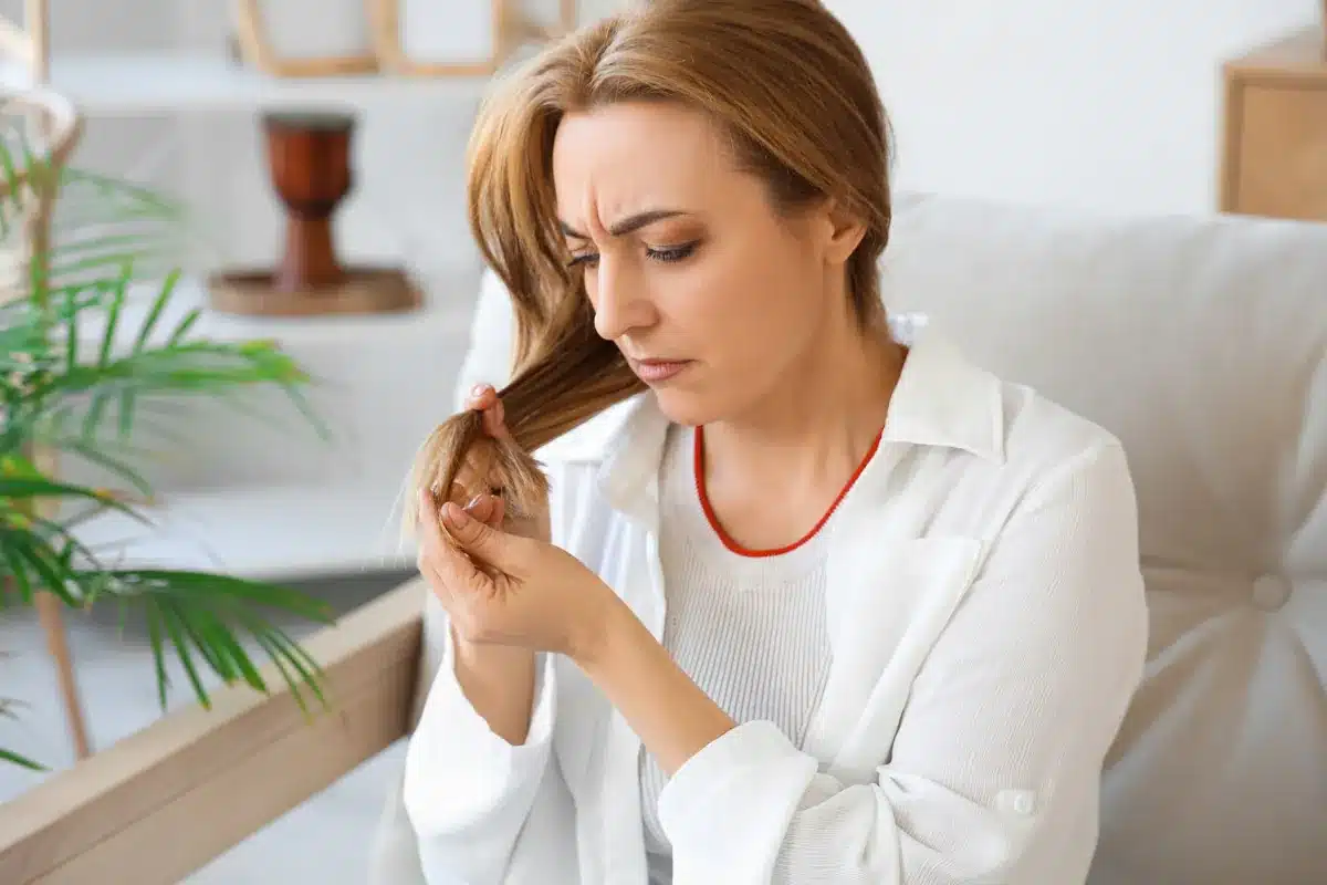 Mulher analisando pontas ressecadas em cabelo fino e danificado
