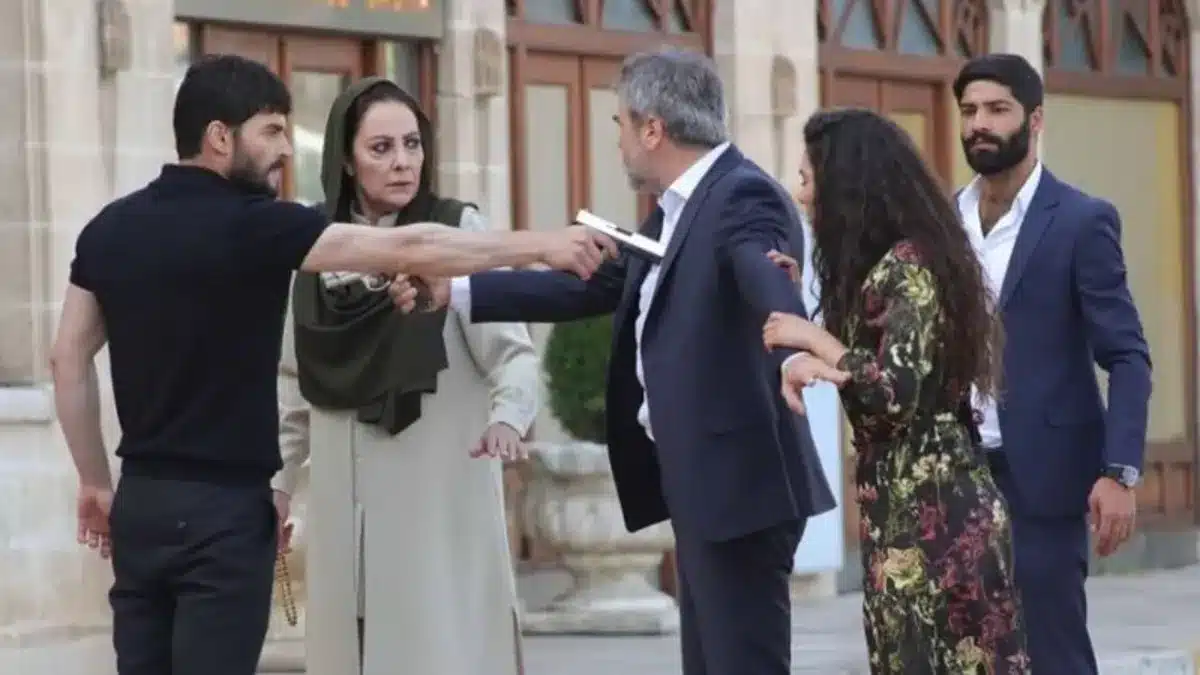 Cena de ação de uma novela turca, com personagens em confronto dramático, destacando um momento tenso com uma arma em cena.
