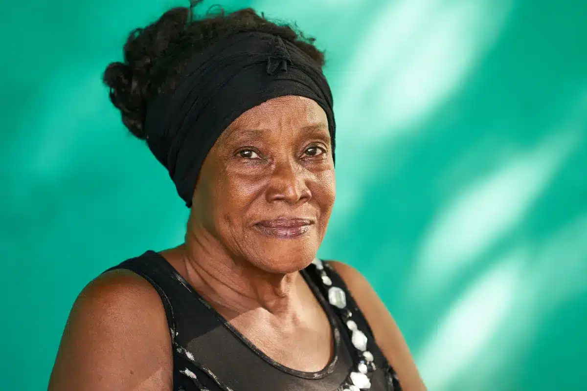 Idosa sorrindo em frente a fundo verde.