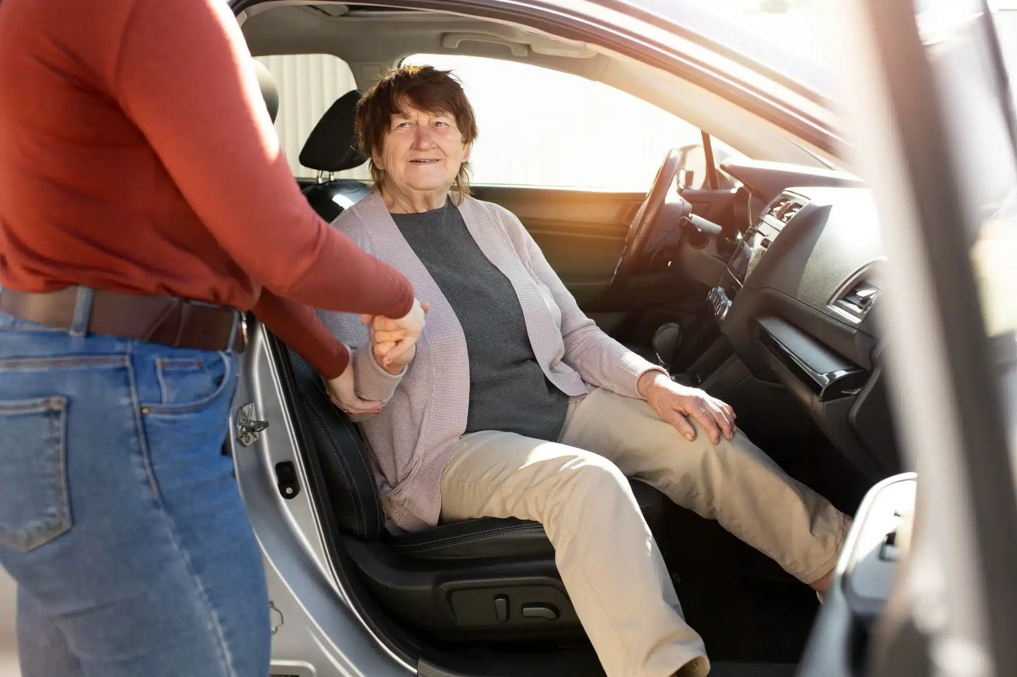 Pessoa ajudando um idoso a sair de um carro, simbolizando a possibilidade de nomear um representante legal para dirigir o veículo.