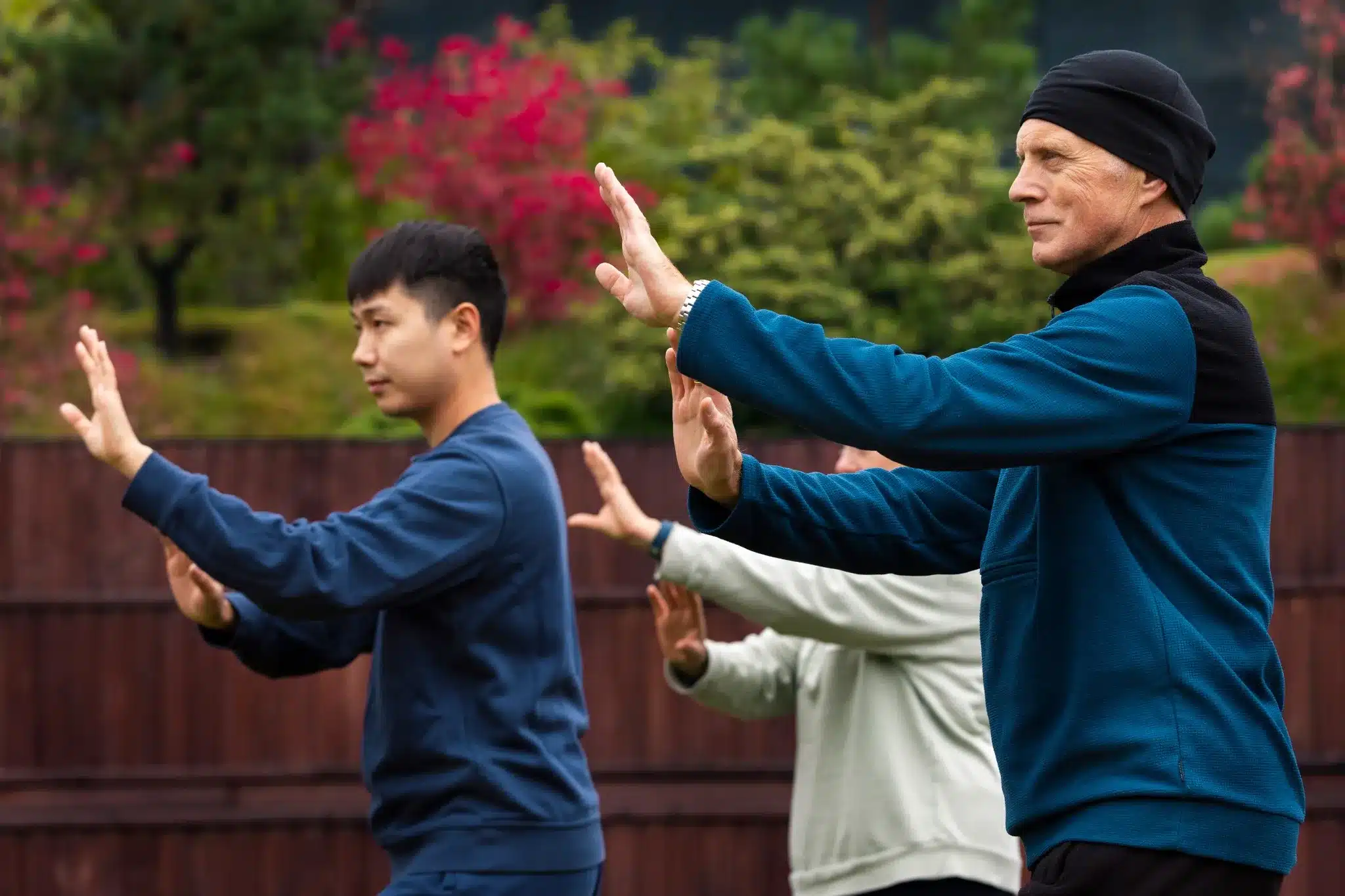 Prática de Tai Chi Chuan ao ar livre Grupo de pessoas praticando Tai Chi Chuan ao ar livre, com foco em movimentos suaves e controlados, adequado para idosos.