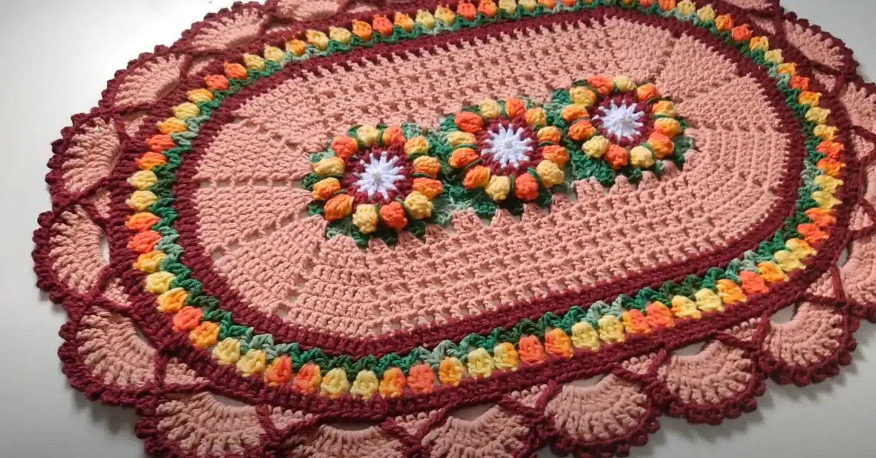 Tapete de crochê oval com flores coloridas em tons outonais.