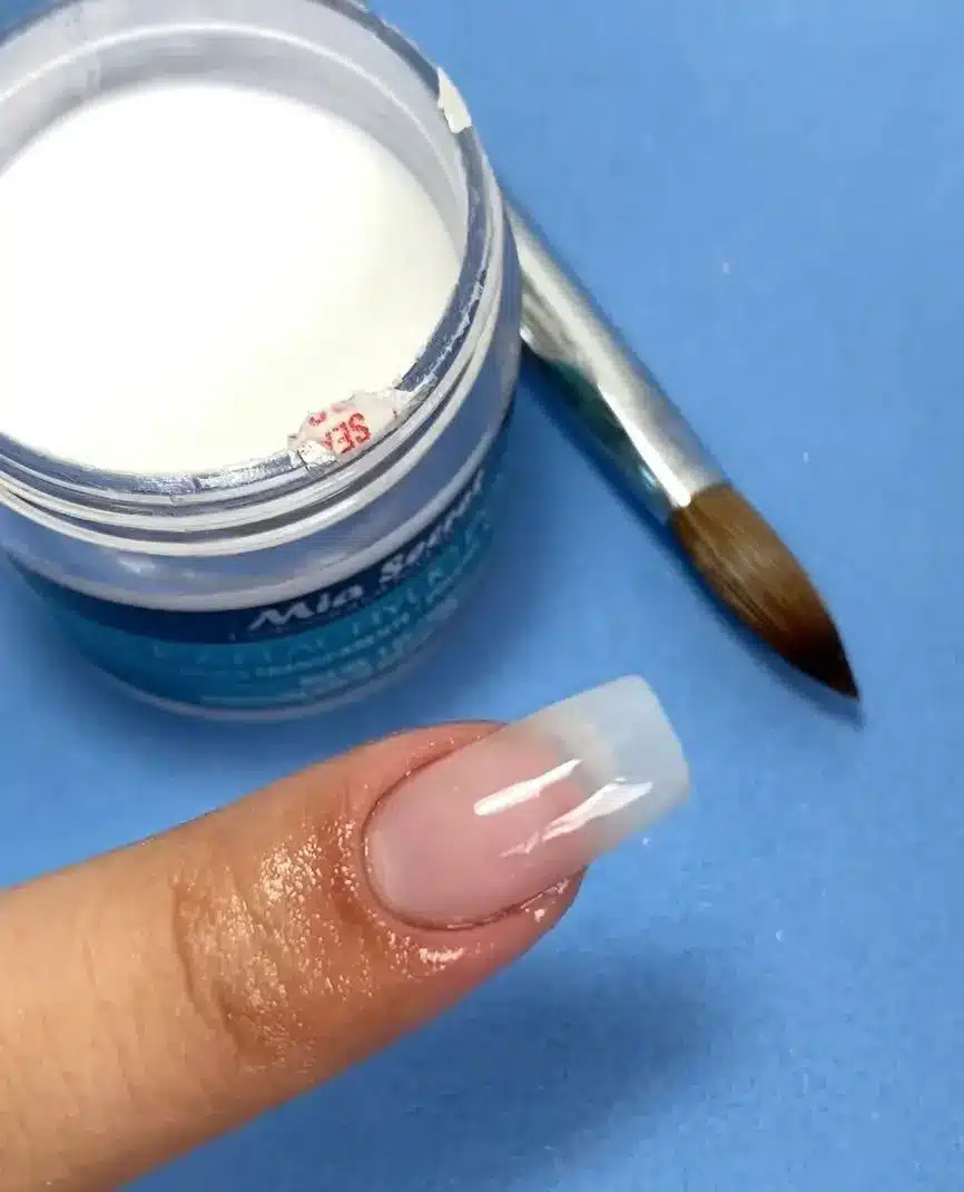 Unha de porcelana com acabamento francês, mostrando a aplicação do pó na ponta.