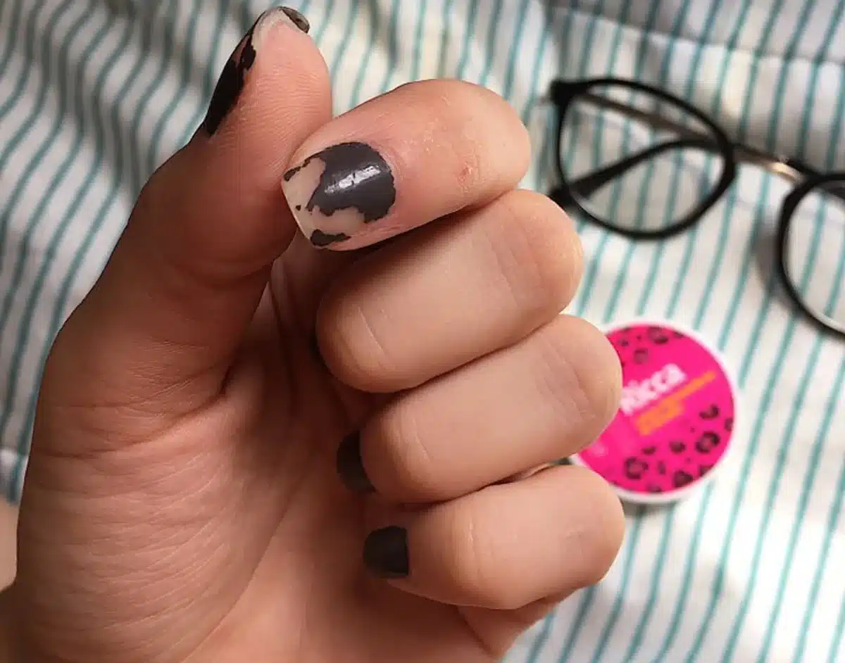 Unha com esmalte descascando, mostrando erro na aplicação.