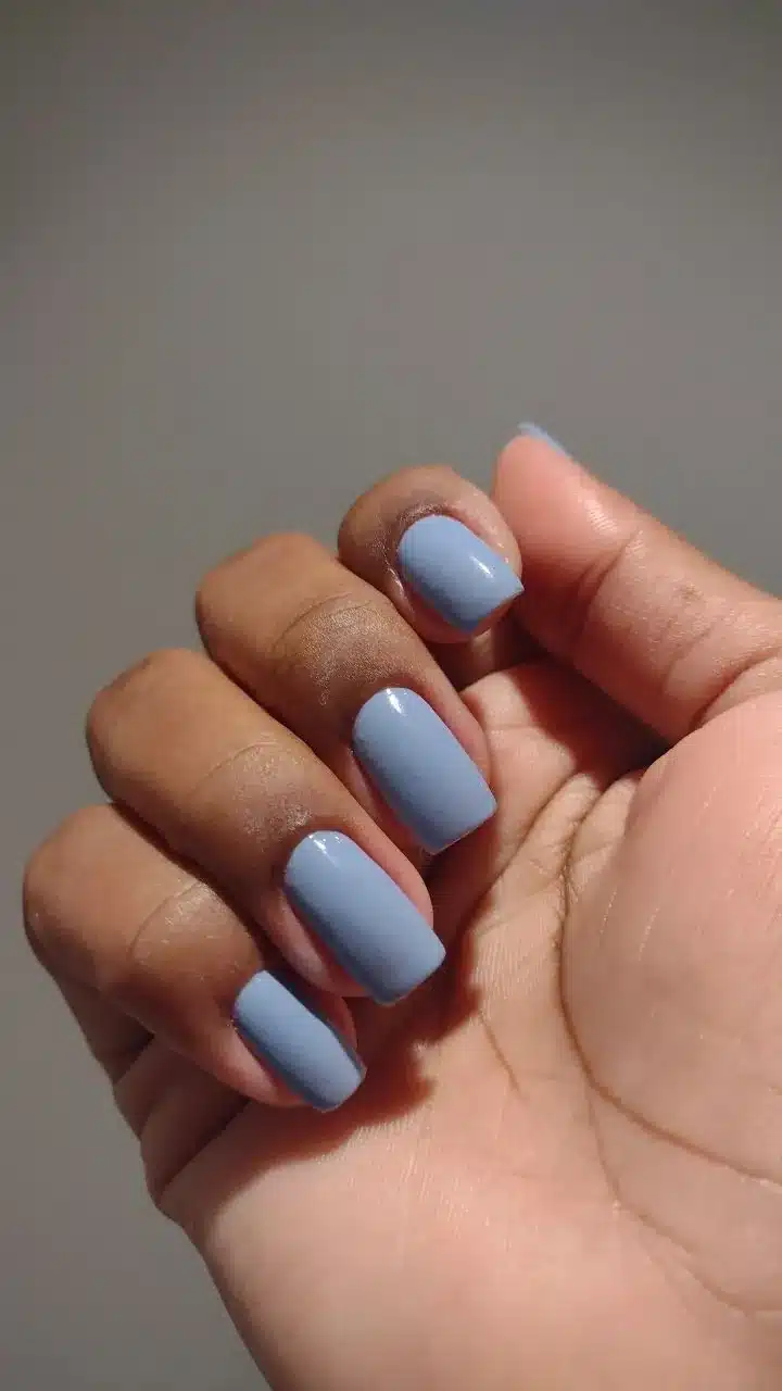 Mão com unhas pintadas em esmalte azul claro