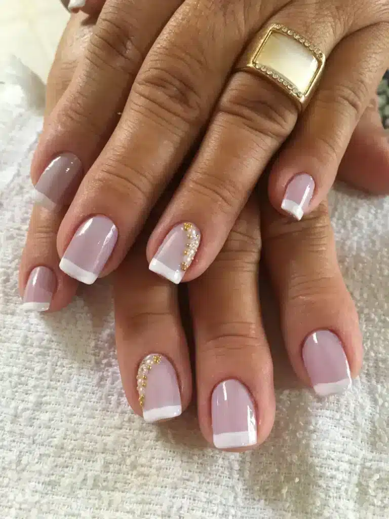 Unhas decoradas com pedrarias douradas e francesinha branca