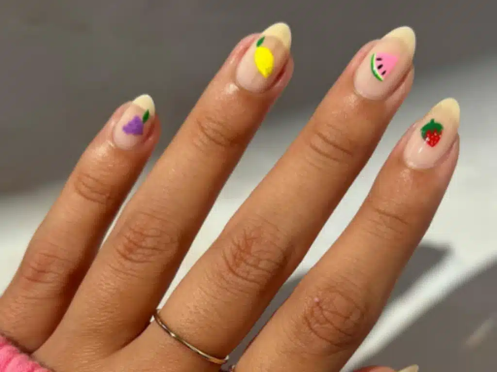 Unhas decoradas com estampas de frutas, como uva, limão, melancia e morango, estilo delicado da nail art japonesa.