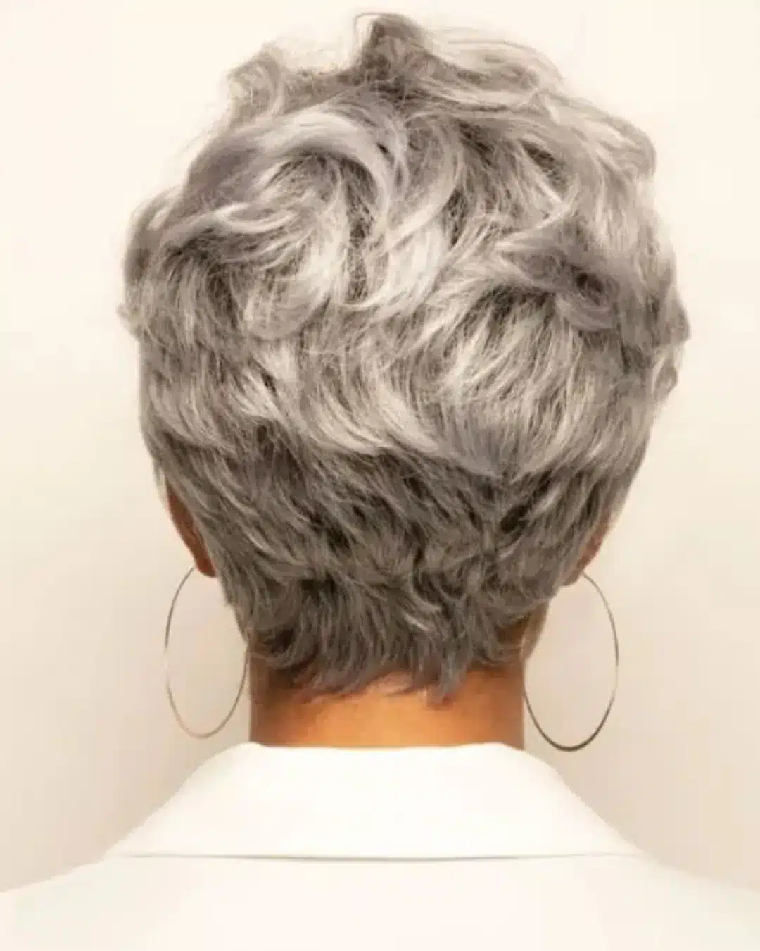 Vista traseira de corte de cabelo curto e cacheado em mulher com fios grisalhos.