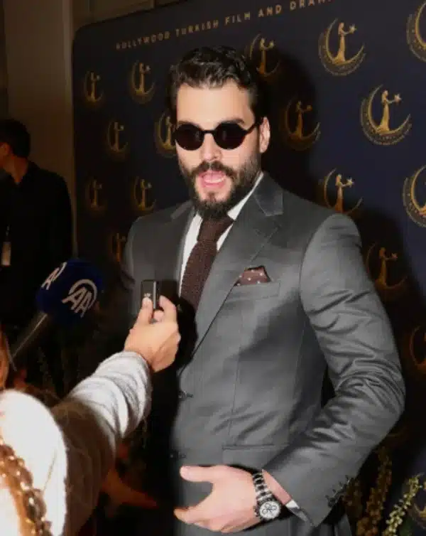 Akin Akinözü, ator de 'Hercai: Amor e Vingança', em evento com terno e óculos escuros
