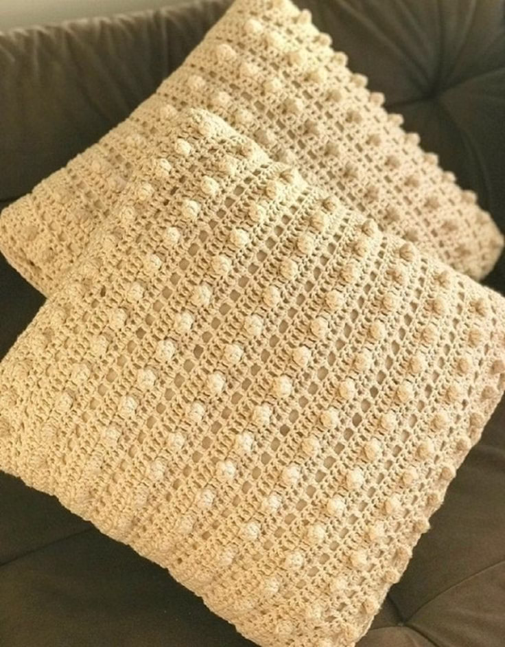 Capa de almofada bege feita em crochê com ponto pipoca