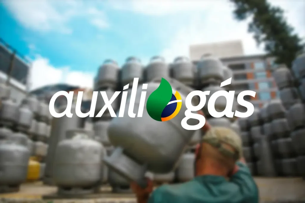 Homem carrega botijão de gás próximo a pilha de cilindros, com o logo do Auxílio Gás em destaque.