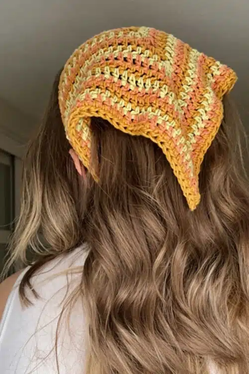 Bandana de crochê em tons de amarelo e laranja, com um padrão listrado