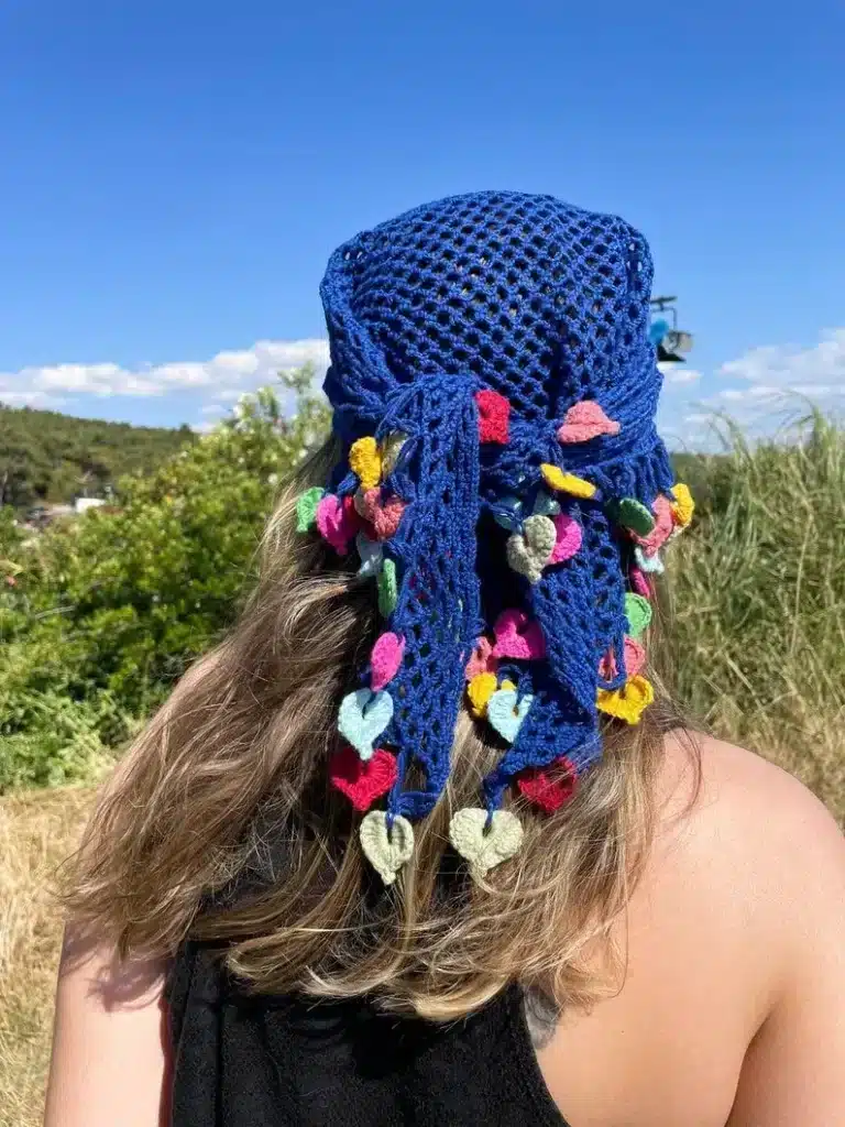 Bandana de crochê colorida com corações, popular na moda praia europeia, amarrada na cabeça.