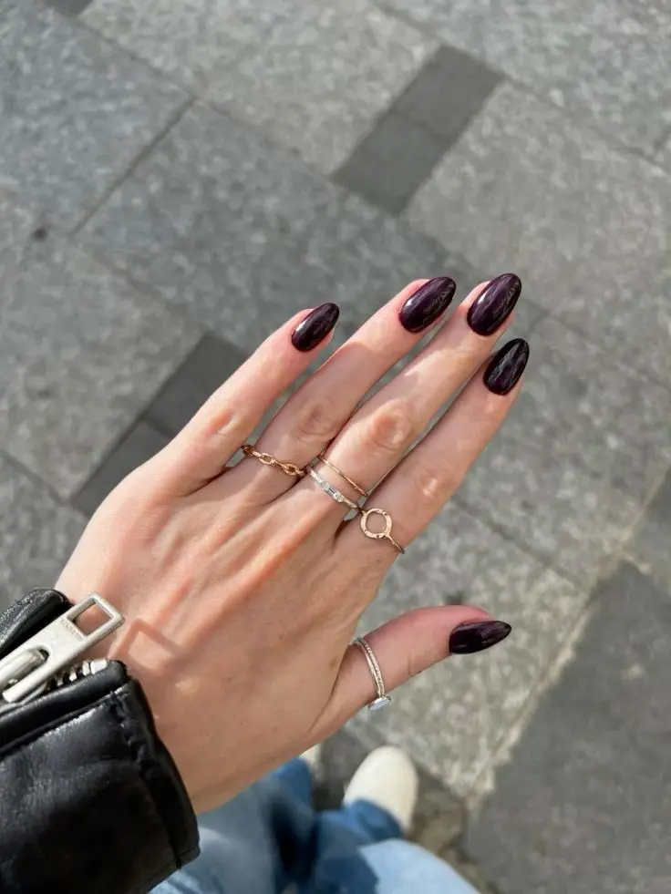 Unhas pintadas com esmalte roxo beringela, destacando o tom profundo e elegante.