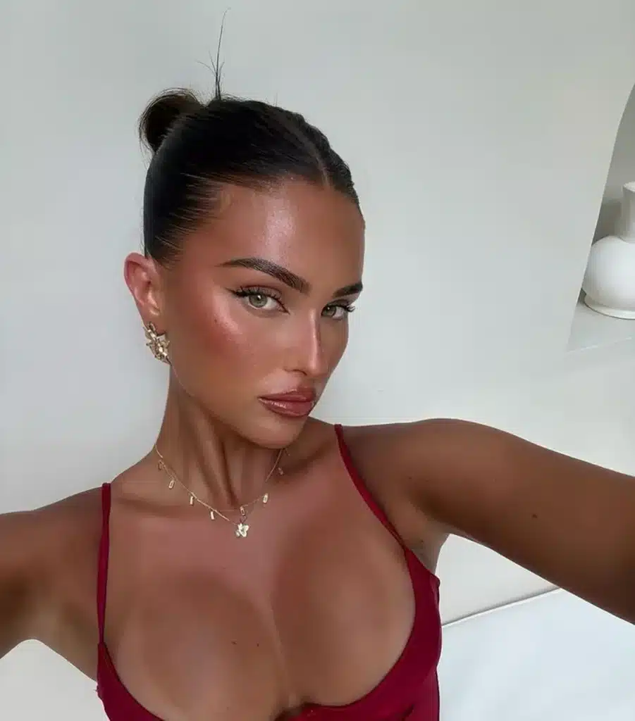 Coque moderno e simples: passo a passo para um look rápido Mulher com coque moderno, maquiagem natural e usando acessórios delicados.