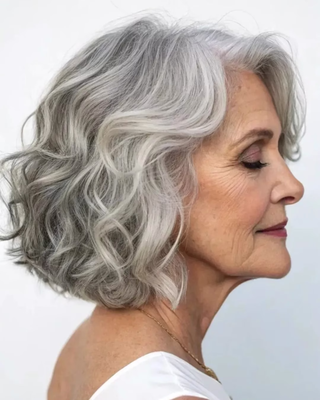 Mulher com cabelo grisalho curto em corte em camadas e ondulado.