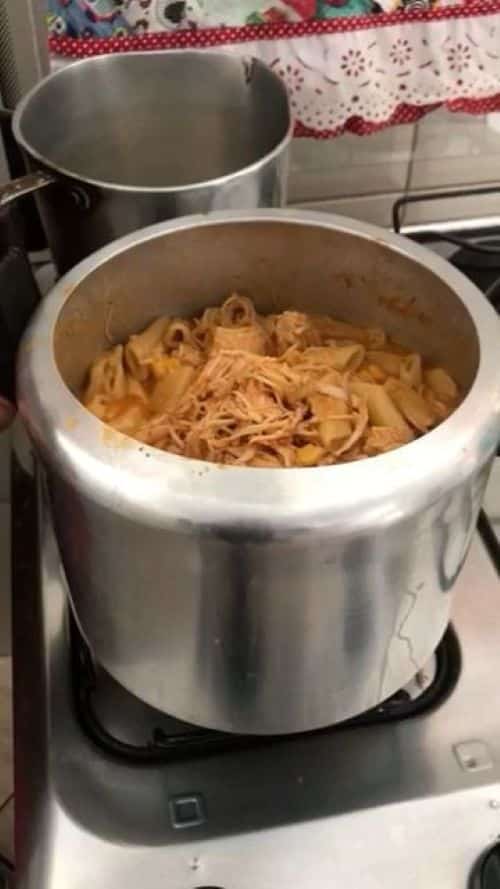 Macarrão cozido em uma panela de pressão, com molho e frango desfiado, pronto para ser servido.