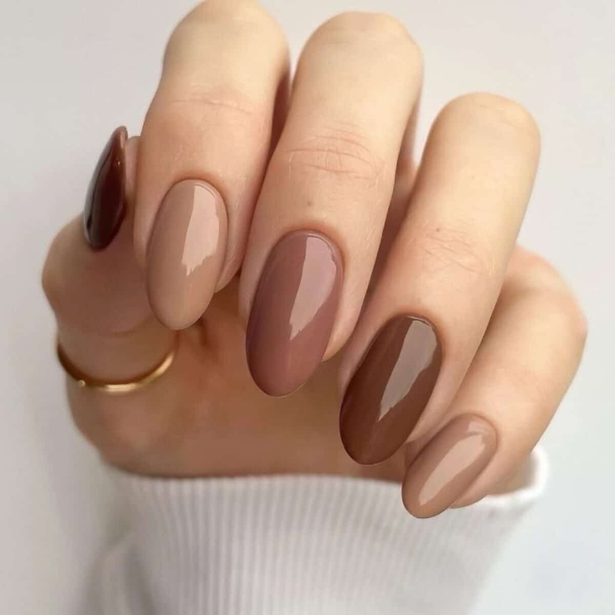 Unhas de manicure sofisticada em tons de marrom, com acabamento brilhante e minimalista.