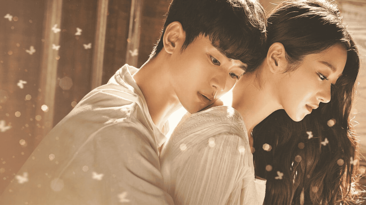 Cena emocionante de Tudo Bem Não Ser Normal, com Moon Gang-tae e Ko Moon-young, onde ele a abraça de forma protetora. A imagem é iluminada com borboletas esvoaçantes, simbolizando a cura e o crescimento emocional do casal ao longo da série.