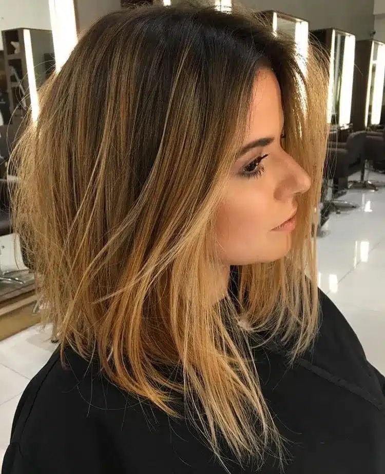 Corte de cabelo long bob assimétrico, com tons de loiro e textura natural.