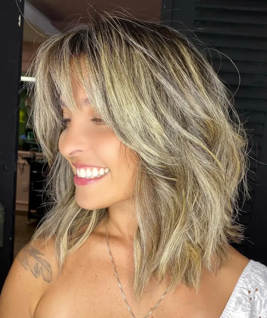 Mulher sorrindo com cabelo loiro repicado em long bob