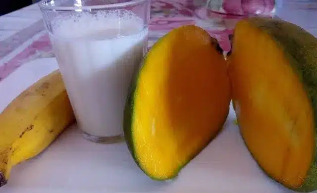Manga cortada com leite ao fundo