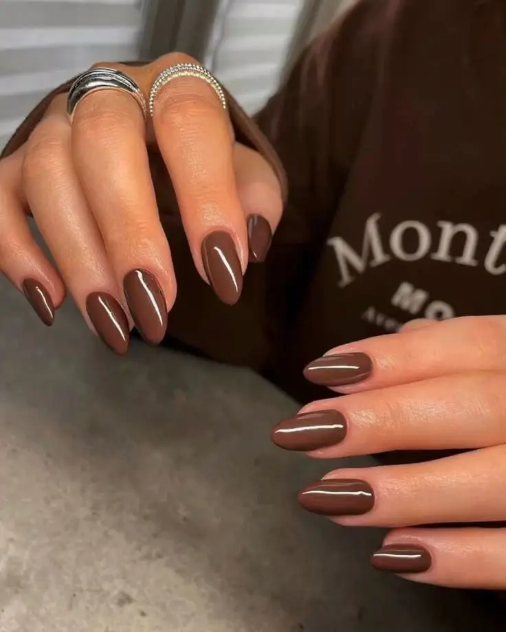 Unhas pintadas com esmalte marrom, destacando o acabamento elegante e sofisticado da cor.