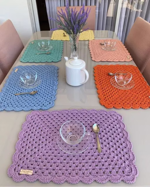Sousplats de crochê coloridos em tons vibrantes sobre a mesa, destacando o contraste e trazendo alegria à composição.