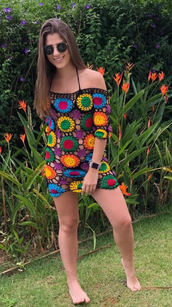 Mulher usando um vestido de crochê multicolorido com flores em fundo natural