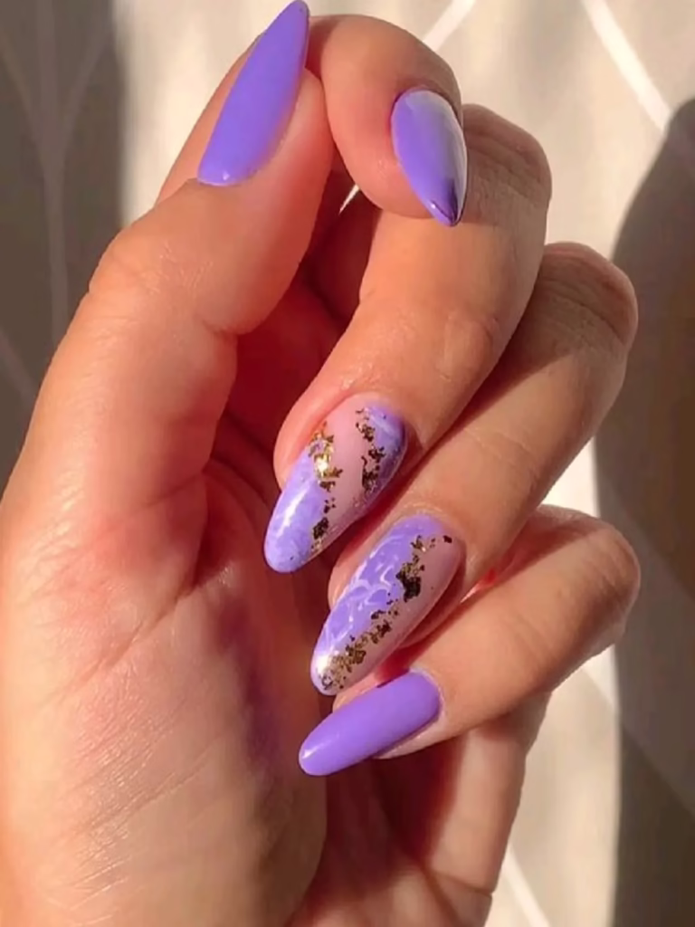 Unhas decoradas em lilás com detalhes marmorizados e folhas douradas