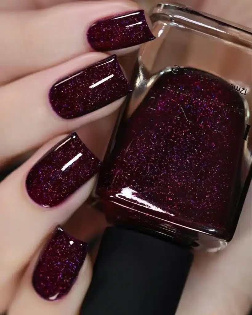 Unhas com esmalte vinho escuro glitter, criando um efeito cintilante e brilhante.