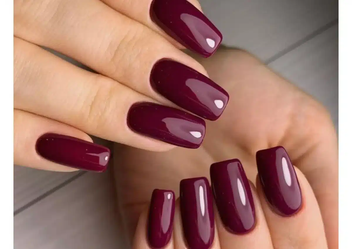 Unhas com esmalte vinho escuro glossy, proporcionando um acabamento brilhante e sofisticado.