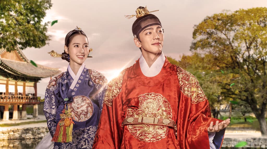 Casal coreano vestido com trajes reais tradicionais (Hanbok) da Dinastia Joseon, representando a série "Rainha: Amor e Guerra".