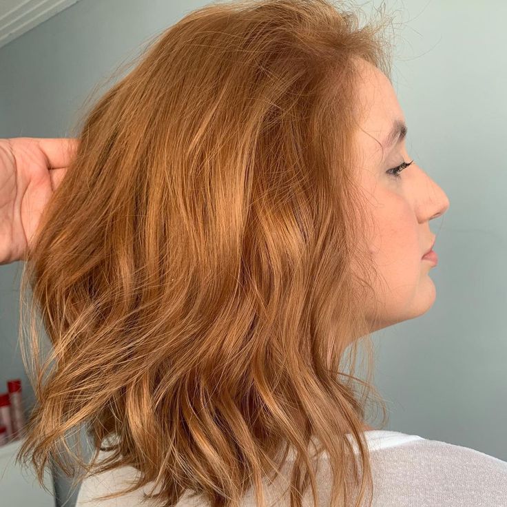 Mulher de perfil, com corte de cabelo curto e ondulado na cor ruivo nude, exemplificando um tom natural e elegante.