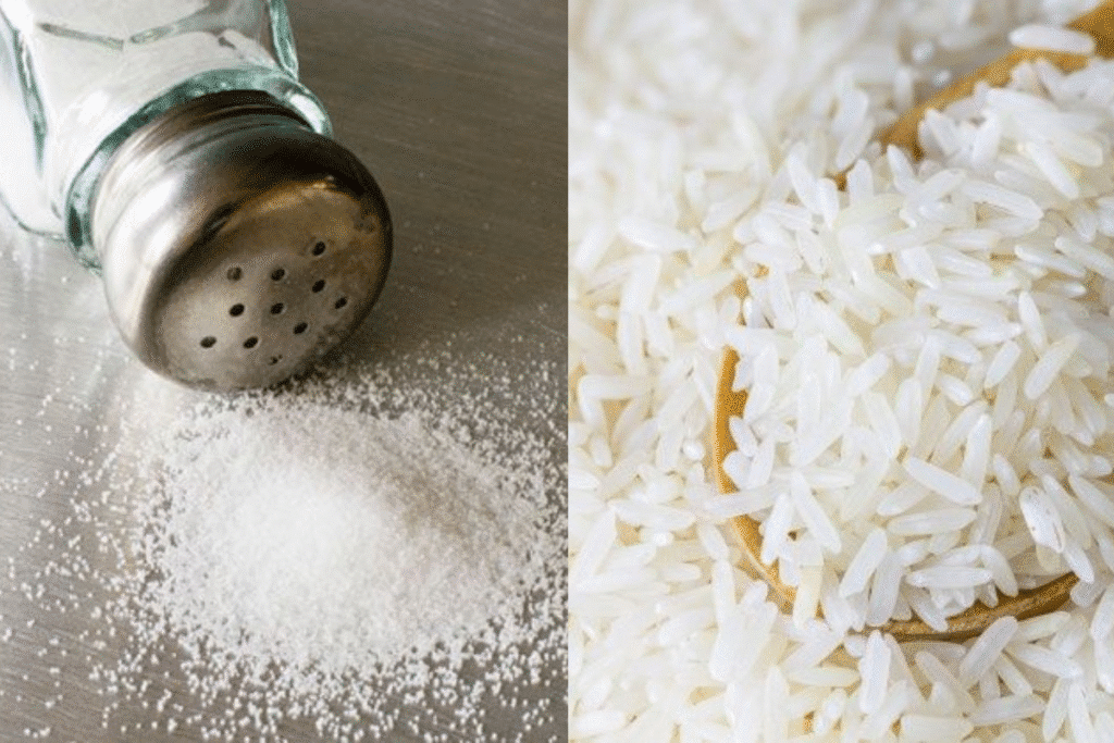 Composição com um saleiro de vidro e sal esparramado, ao lado de grãos de arroz branco, representando o truque para evitar a umidade.