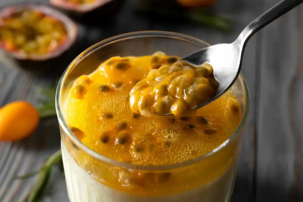 Mousse de maracujá cremoso servido em taça, com uma textura suave e decoração de maracujá fresco.