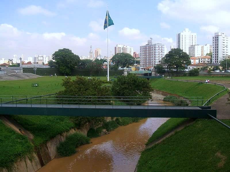 Vista atual do Riacho do Ipiranga, com uma ponte sobre ele e a paisagem urbana ao fundo.