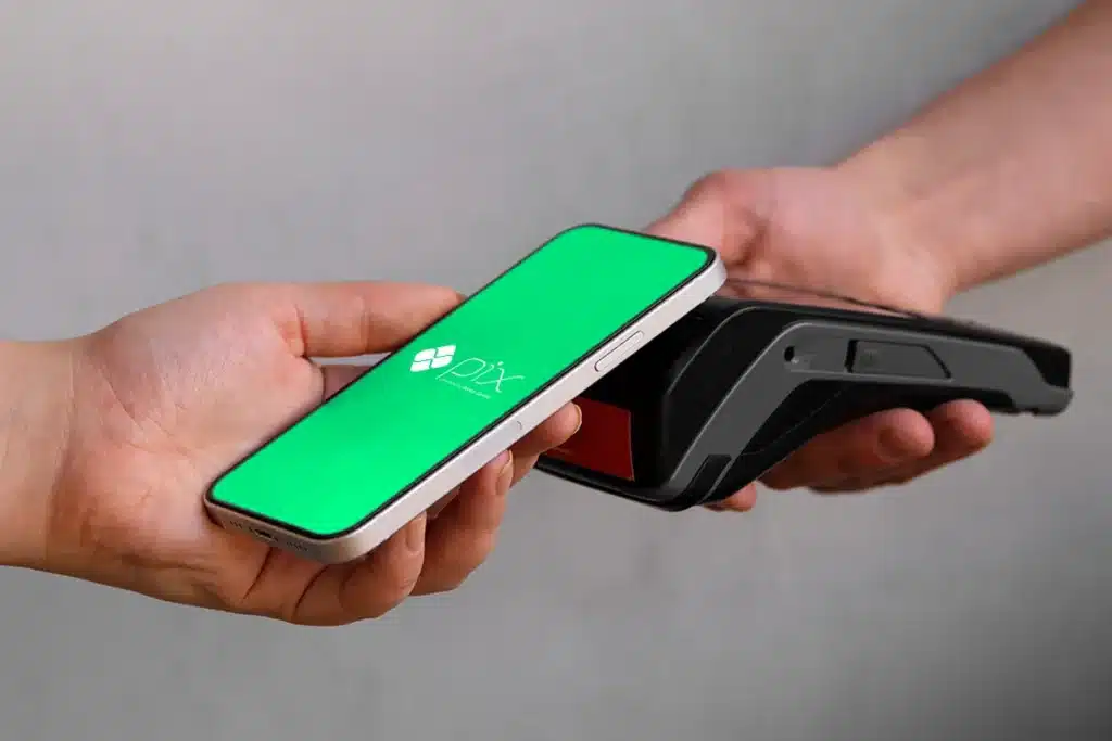 Pessoa realizando pagamento via Pix com smartphone e terminal de pagamento