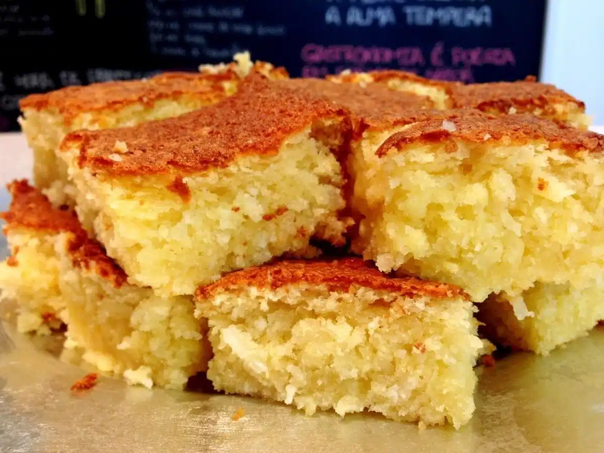 Bolo de mandioca de liquidificador cortado em pedaços, com textura macia e dourada.