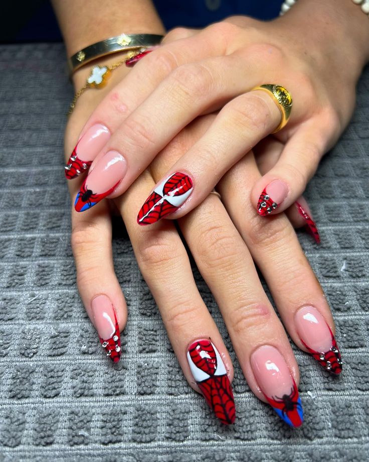 Mãos com unhas decoradas com inspiração no Homem-Aranha, exibindo a teia de aranha, o símbolo do herói e detalhes em vermelho e azul.